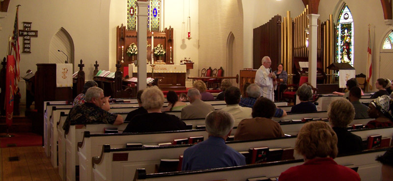 interior of Holy Trinity with congregation seated, rector standing and speaking